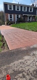 Brick-paved driveway leading to a two-story house with a front lawn