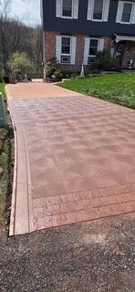 Freshly installed red brick driveway leading to a house with dark siding and a green lawn