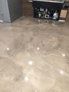 Polished beige tile floor in a kitchen with a cabinet and cleaning supplies in the background