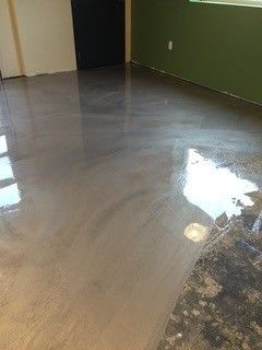 Empty room with glossy gray floor, green wall, and doorway in the background.