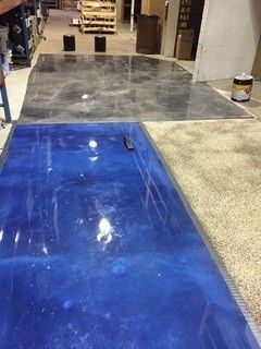 Workshop floor with blue and gray epoxy-coated sections and a small can at the right edge