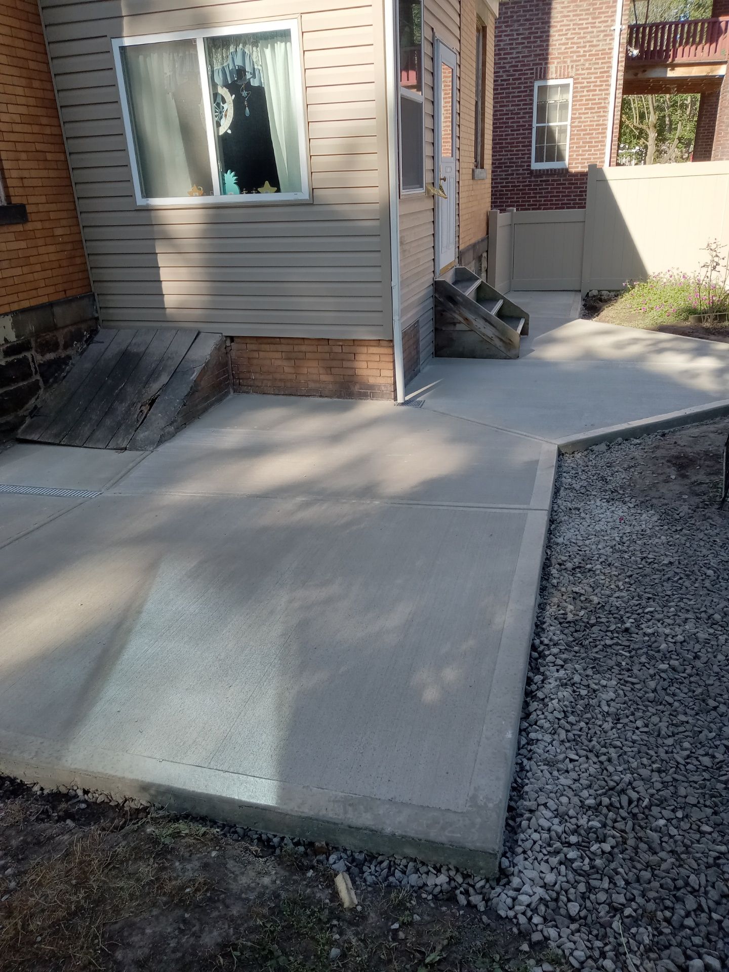 Concrete accessibility ramp beside a house entrance with a handrail and window