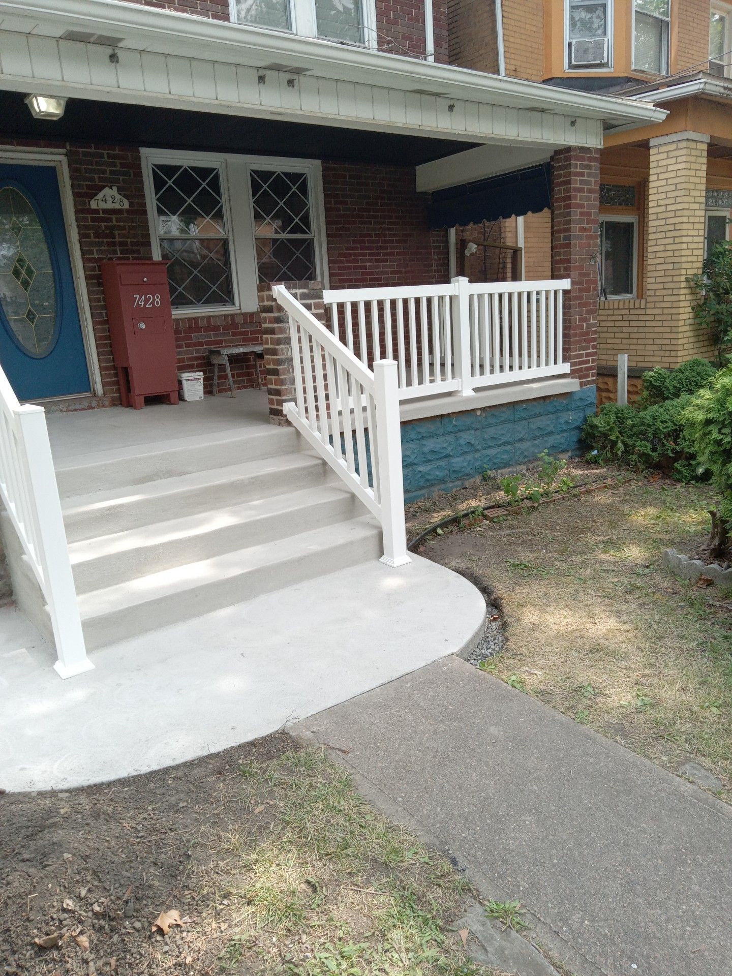Front porch with white steps and railing leading to a brick house entrance