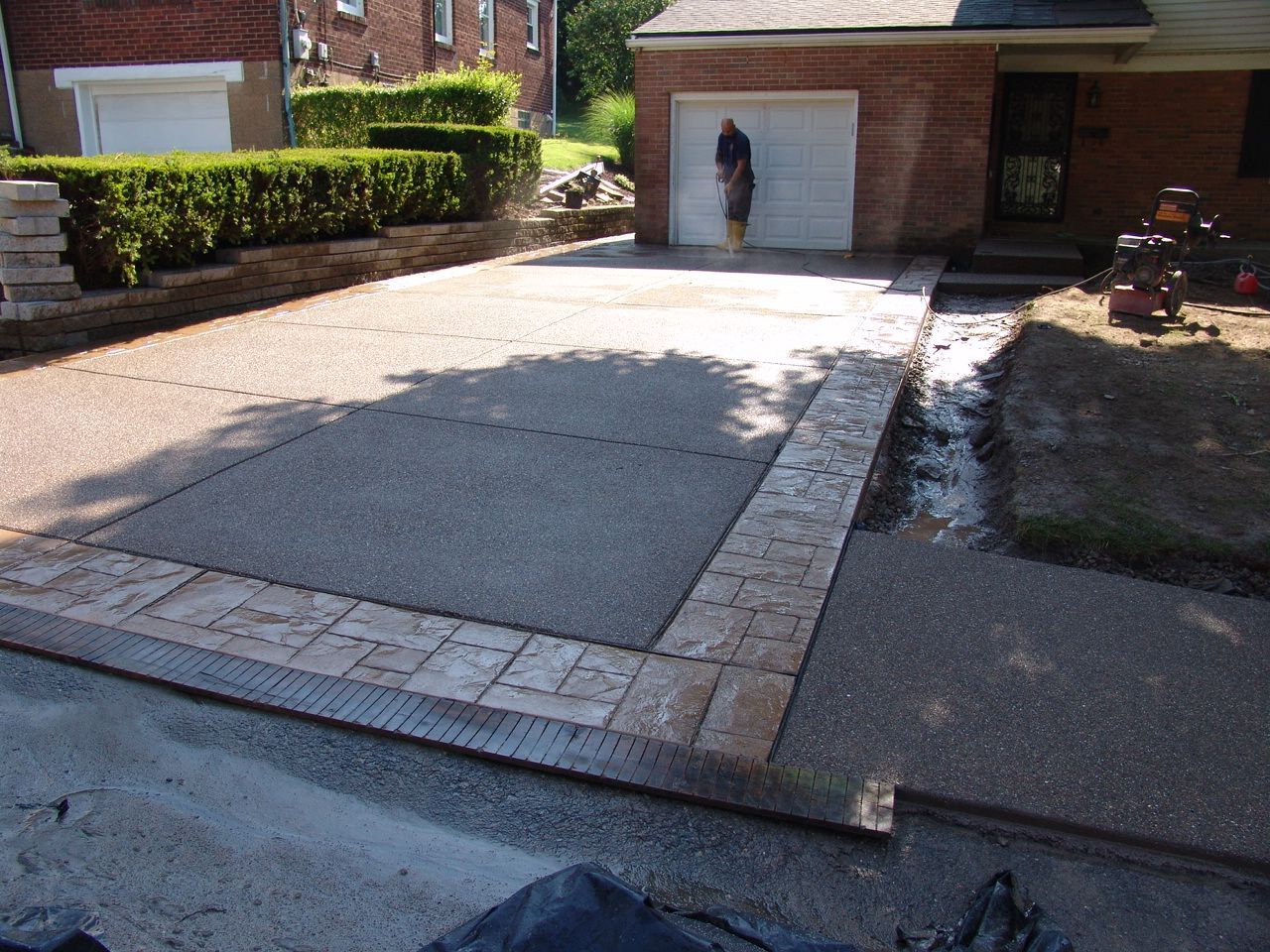 Driveway with a person standing by a garage door beside a brick house