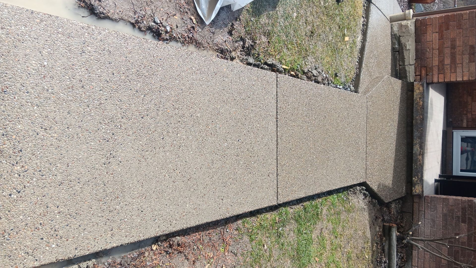 Narrow gravel path between walls leading to a doorway, with mossy edges and a small window on the right.