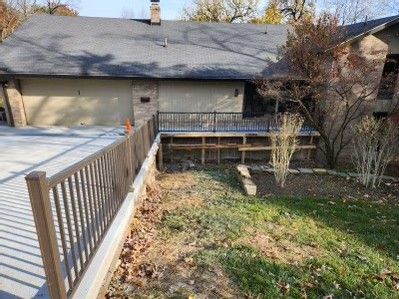 Backyard with wooden deck, fence, lawn, and a house in the background