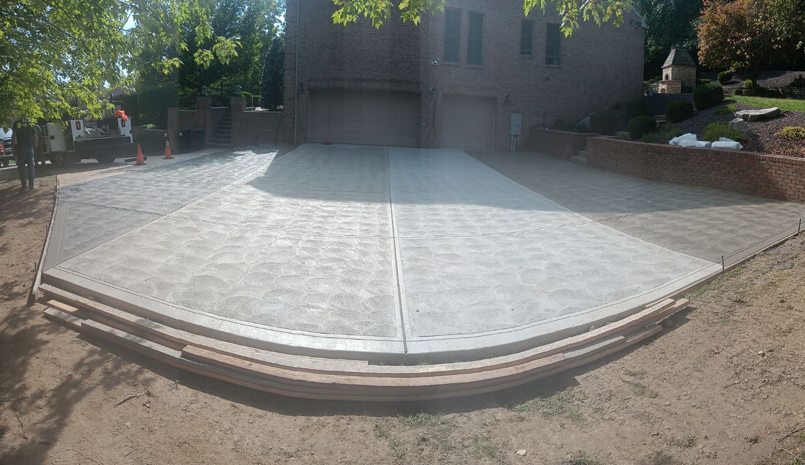 Curved concrete wheelchair ramp with metal edging leading to a building entrance in a sunny courtyard