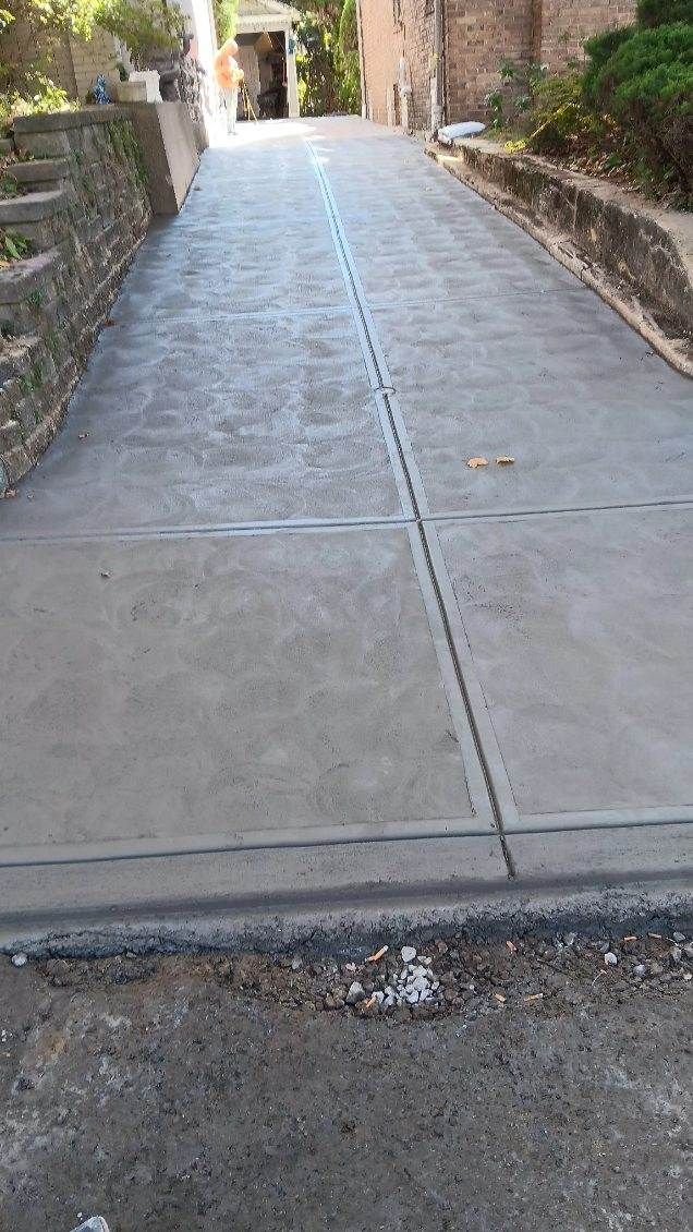 Concrete driveway or walkway with a center crack leading toward a building entrance outdoors