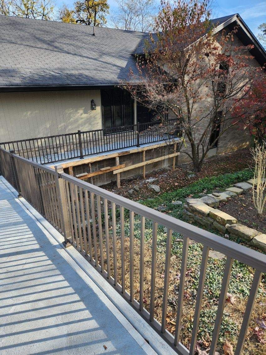 Wooden deck with metal railing overlooking a house and autumn garden