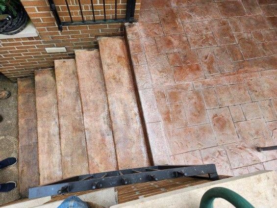 Brick steps leading to a tiled patio beside a brick wall, viewed from above.