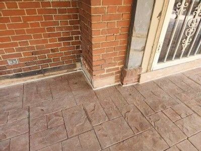 Brick porch corner with tiled floor and a white metal gate beside a brick wall