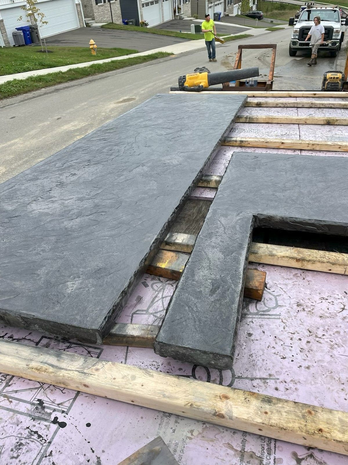 Road crew paving a street with a large asphalt patch over utility trenches