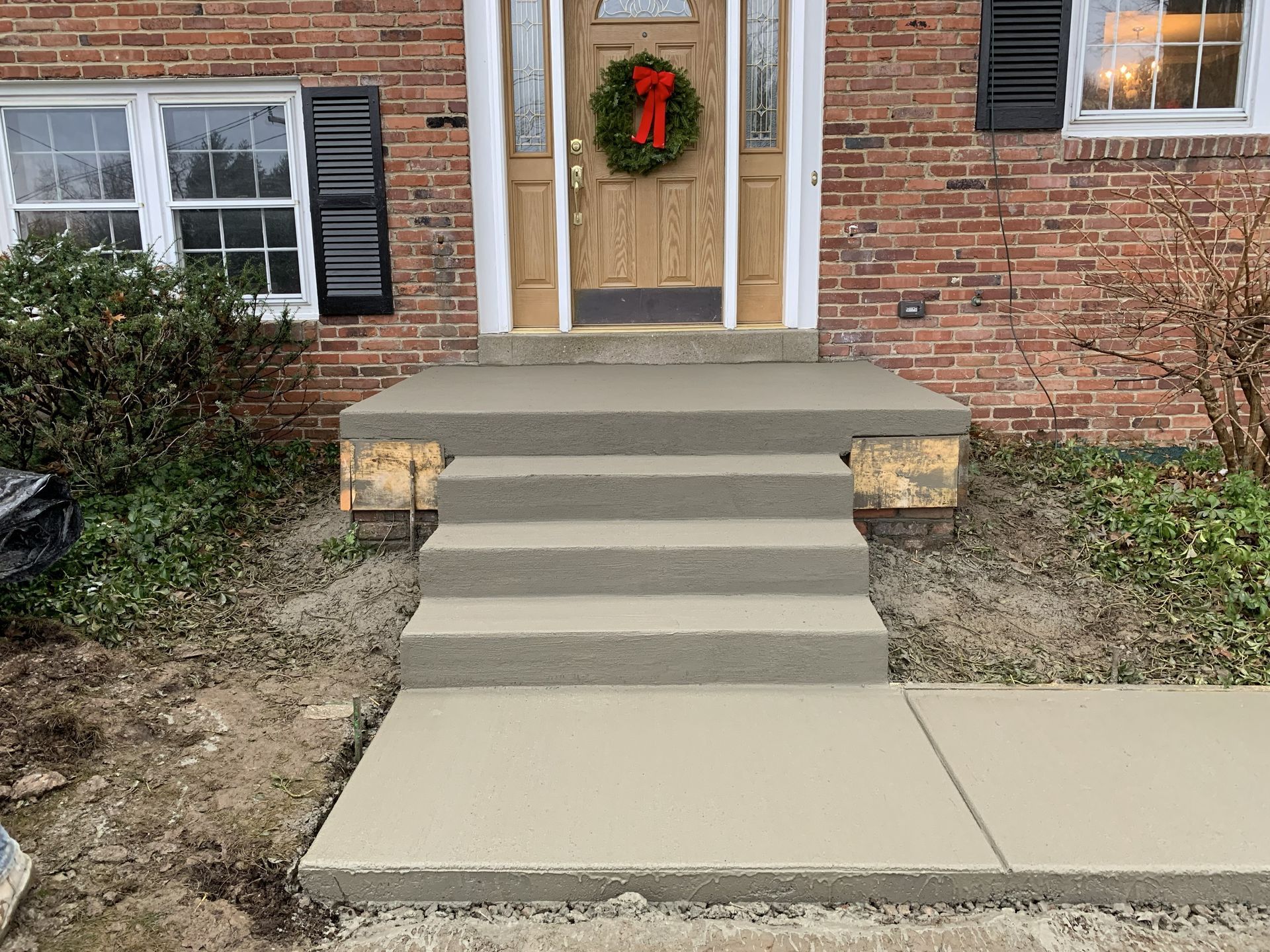 Front steps and walkway leading to a brick house with a wreath on the door