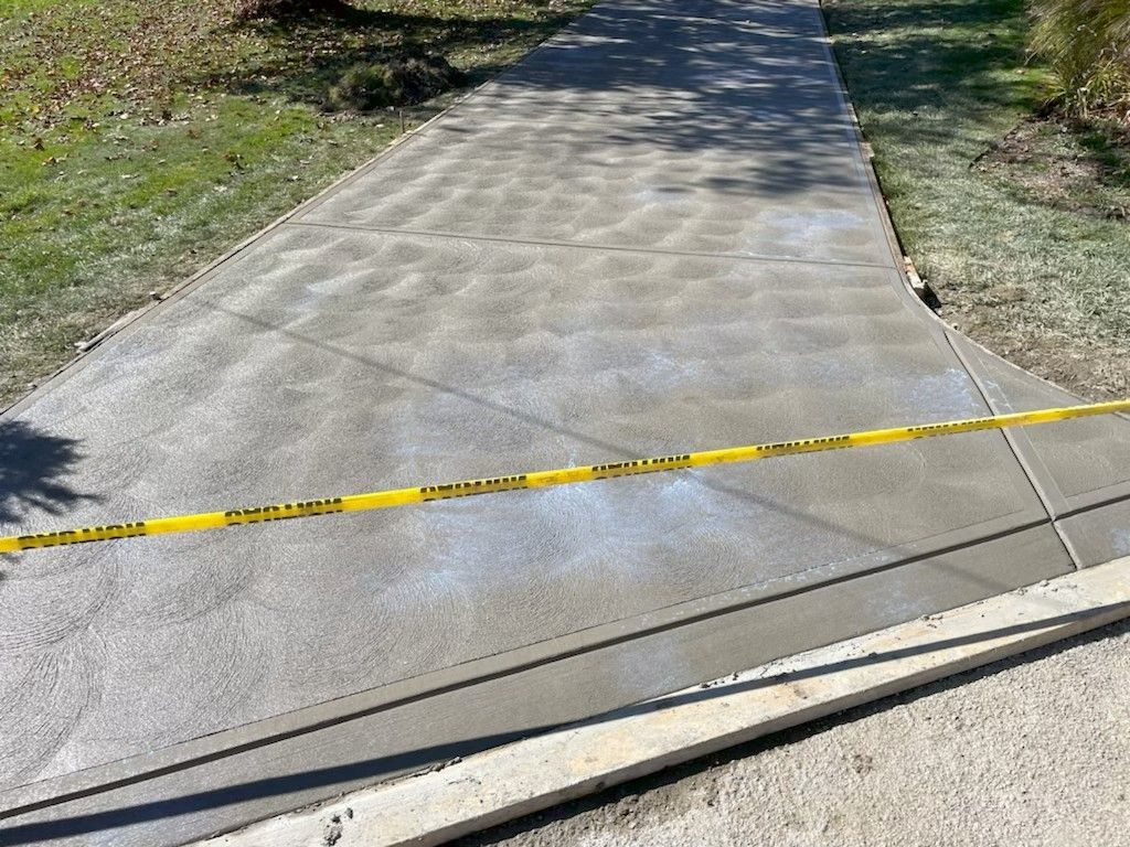 Tape blocking a cracked concrete sidewalk ramp outdoors