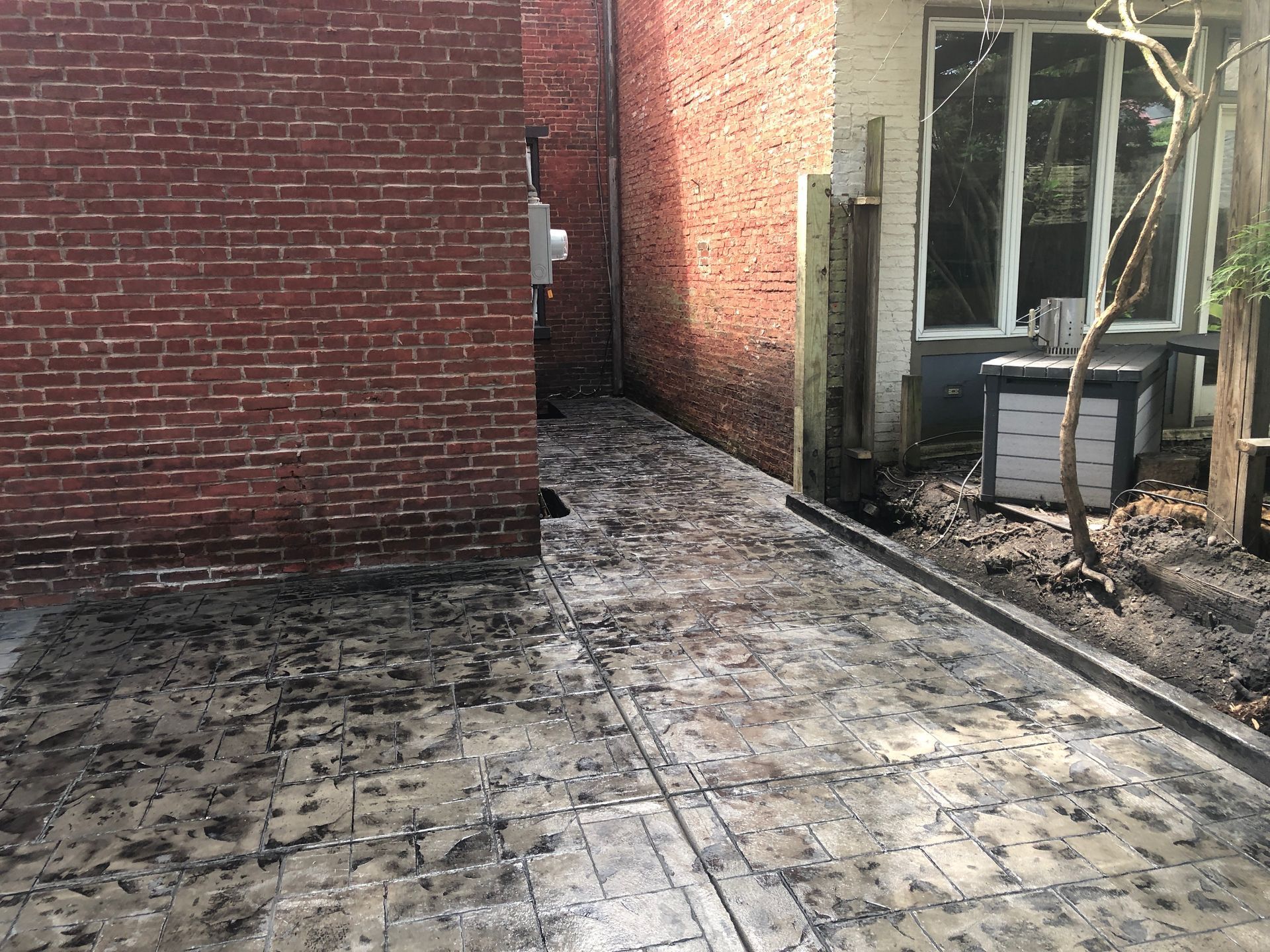 Narrow brick alley with cracked pavement and a windowed building entrance on the right