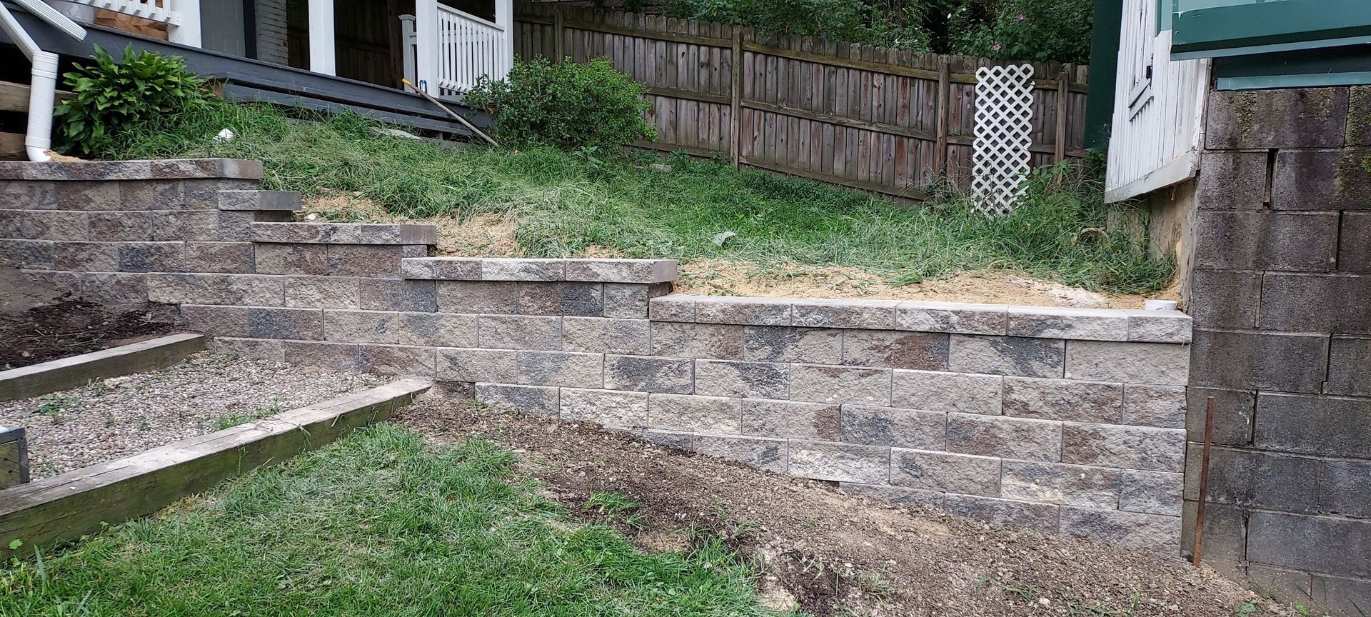 Stone retaining wall and steps beside a grassy yard in a residential outdoor area