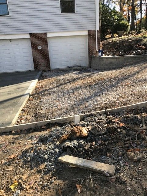 Charred debris and a scorched patch of ground beside a driveway and garage doors