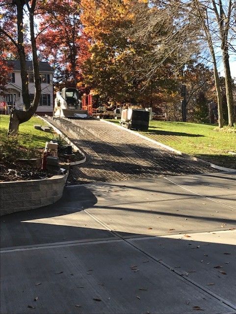 Tree-lined driveway with a black car and autumn foliage at a residential entrance