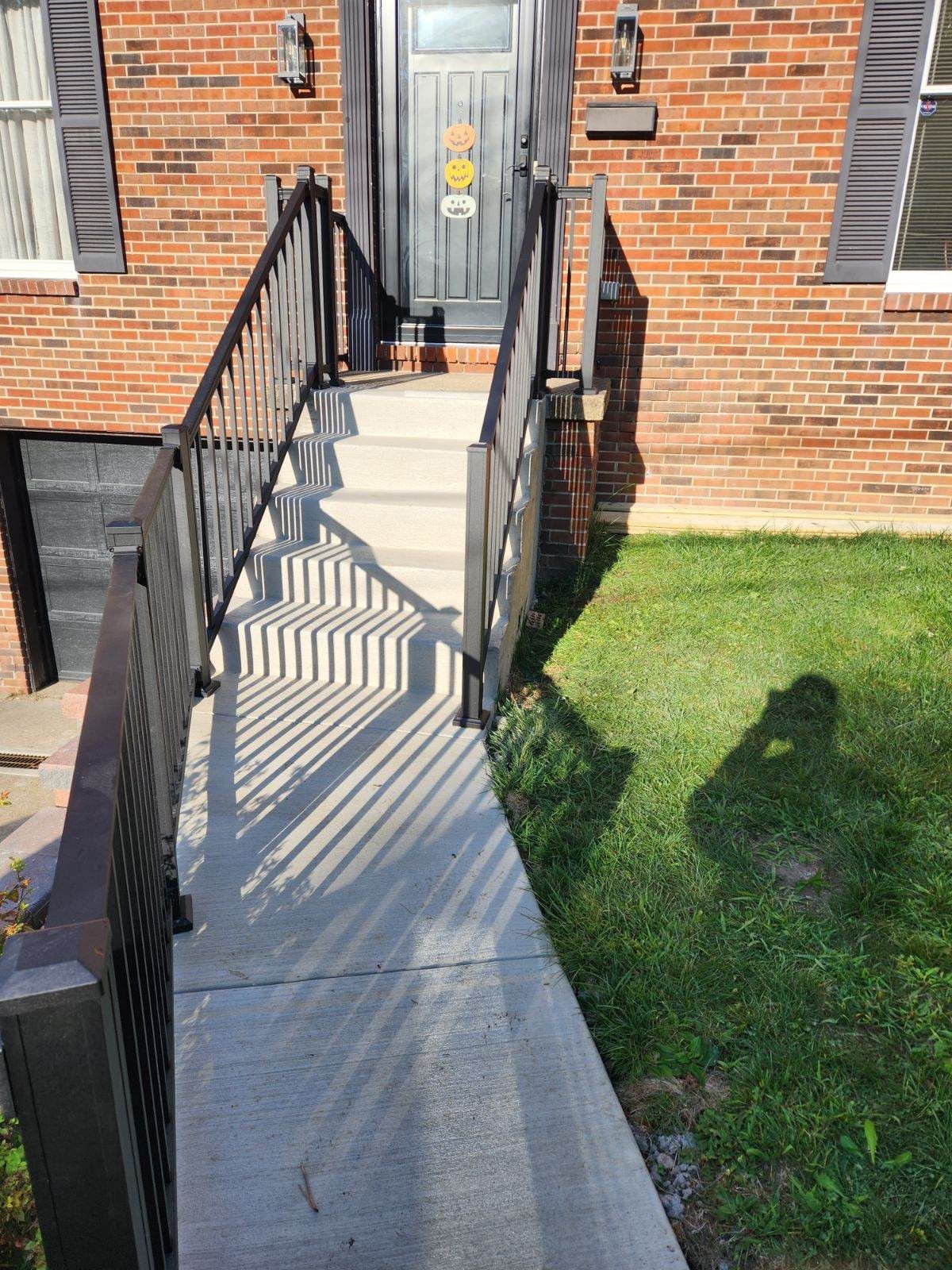 Concrete ramp with black railings leading to a brick building entrance