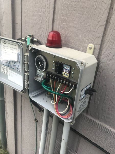 Outdoor electrical control box with open door, timer, and wiring. Red light on top.
