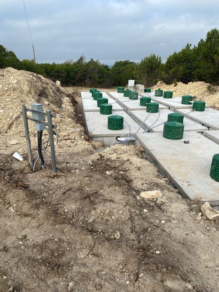Construction site with concrete pads, green coverings, and electrical box.