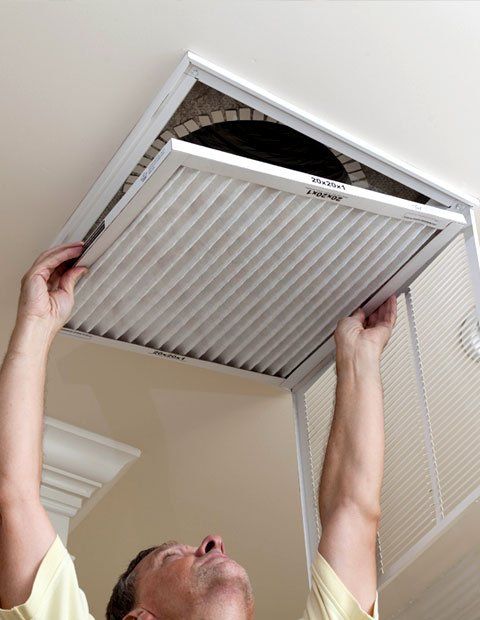 Technician opening filter holder for air conditioning filter in ceiling