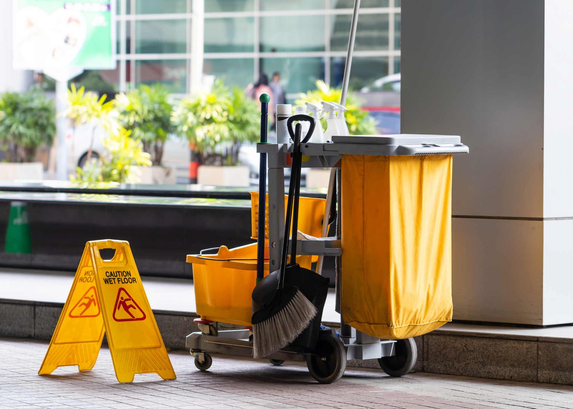 Janitorial cart with mop and yellow warning sign in a building lobby