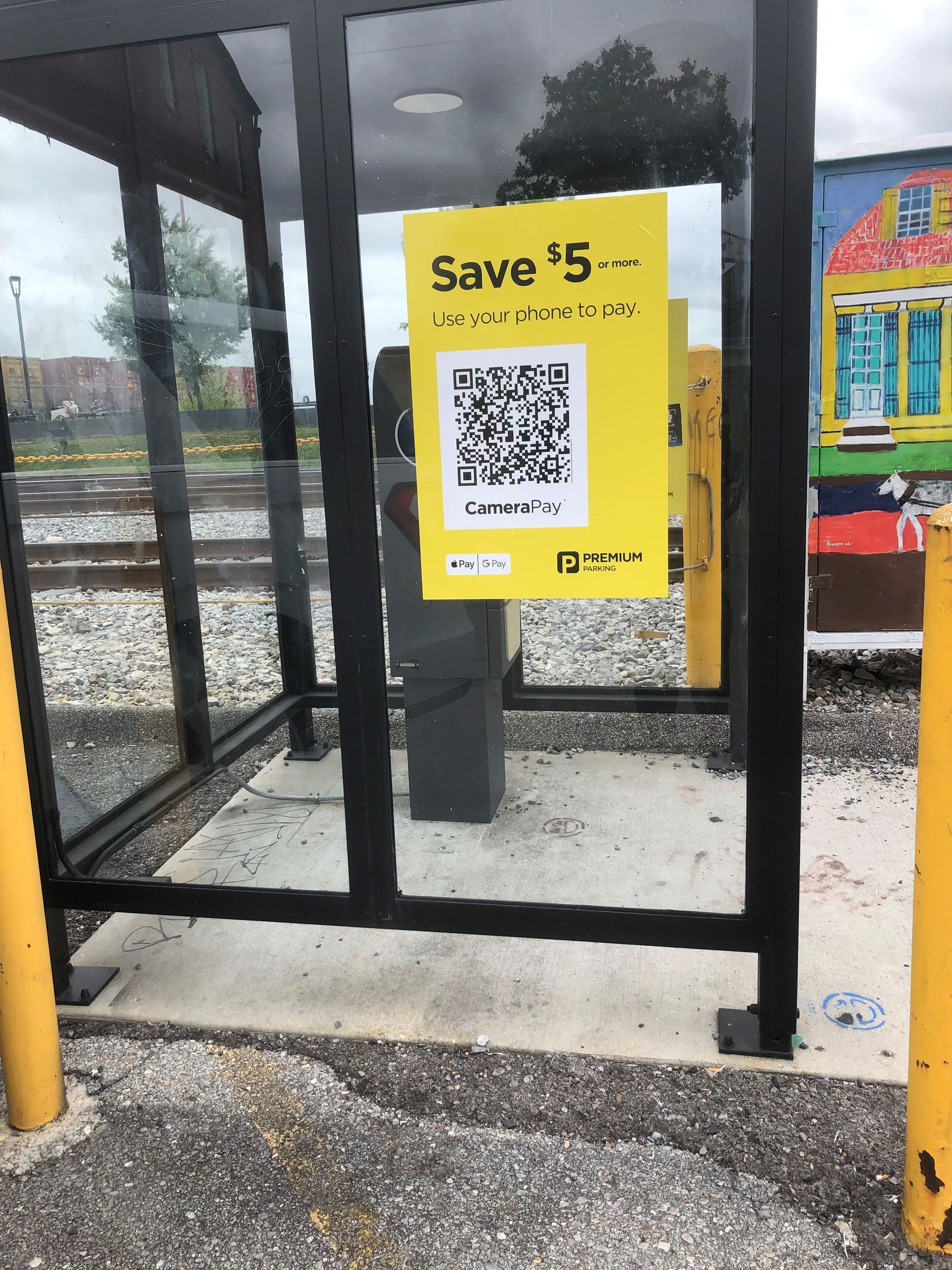 Yellow QR-code sign on a bus shelter glass panel with “Save $5” text.