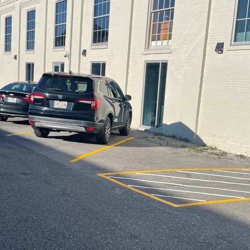Black SUV parked partly in a marked no-parking zone beside a light-colored building