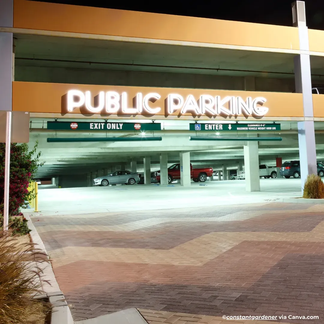 Night view of a public parking garage entrance with illuminated “PUBLIC PARKING” sign and exit/entrance lanes