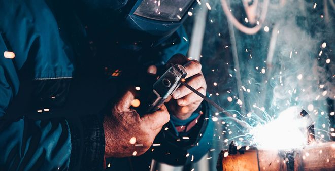 Worker welding metal with bright sparks flying in a workshop