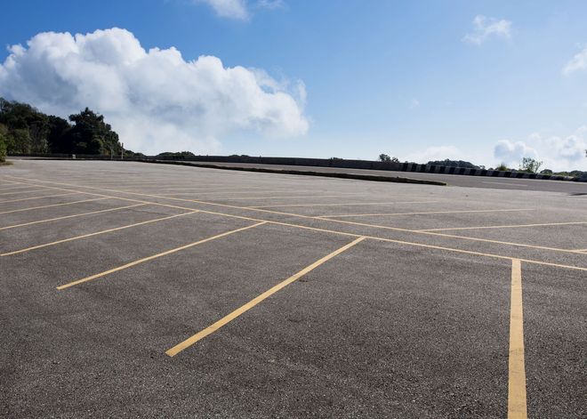 Empty parking lot with yellow lines under a blue sky and clouds