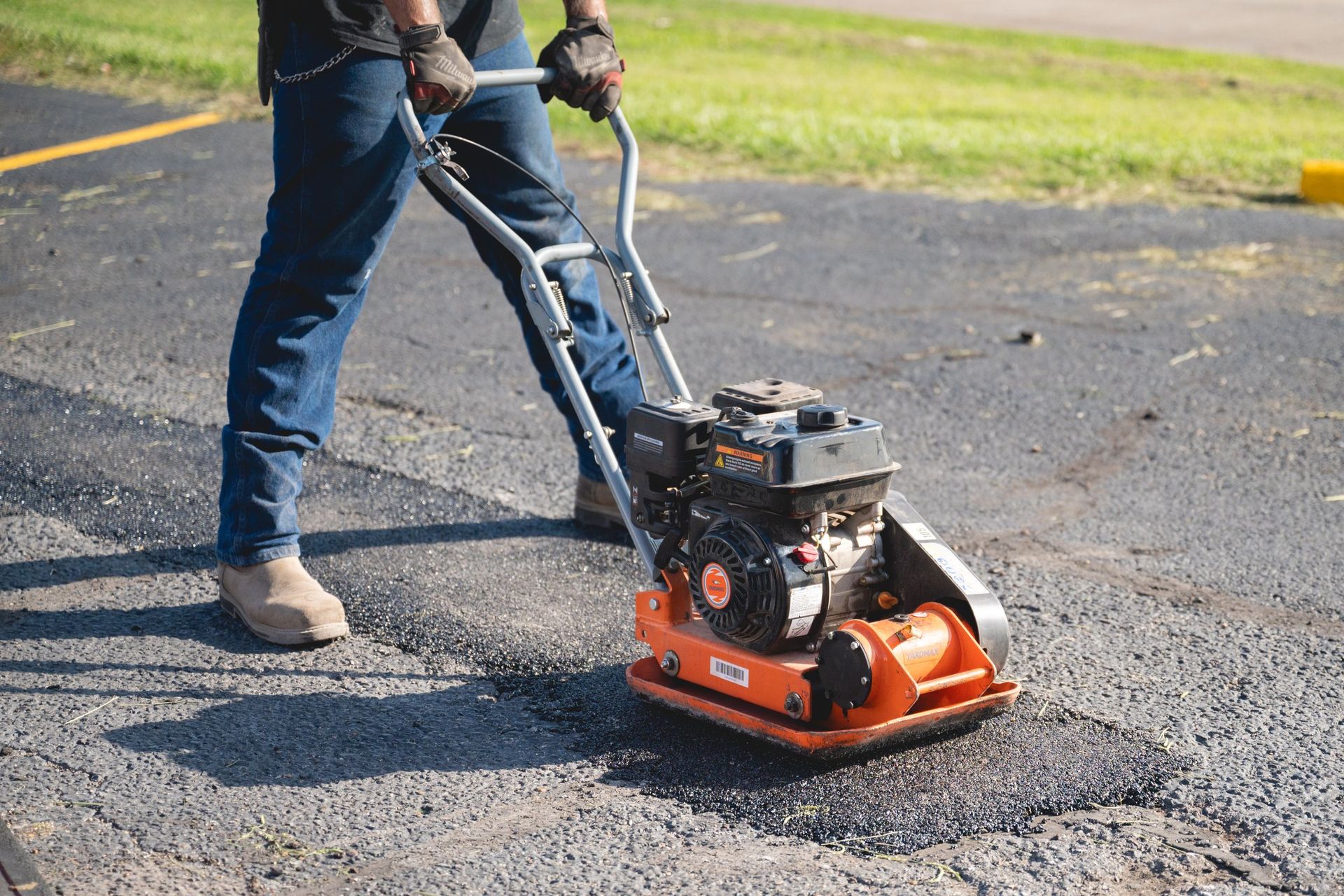 Two potholes patched with gray asphalt on a rough, cracked road surface