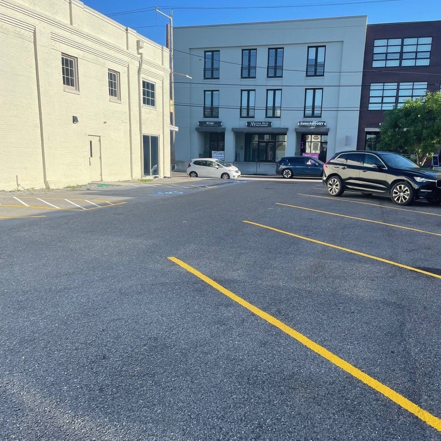 Parking lot striping with white lines and text “PAVEMENT STRIPING DONE RIGHT” on dark asphalt