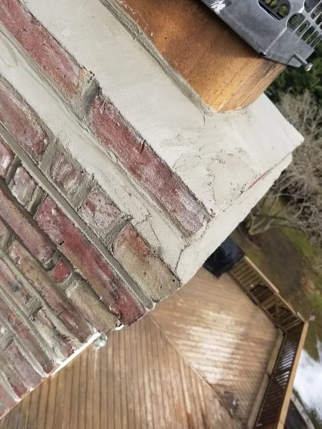 Close-up of a brick wall and white ledge beside a wooden deck and garden fence.