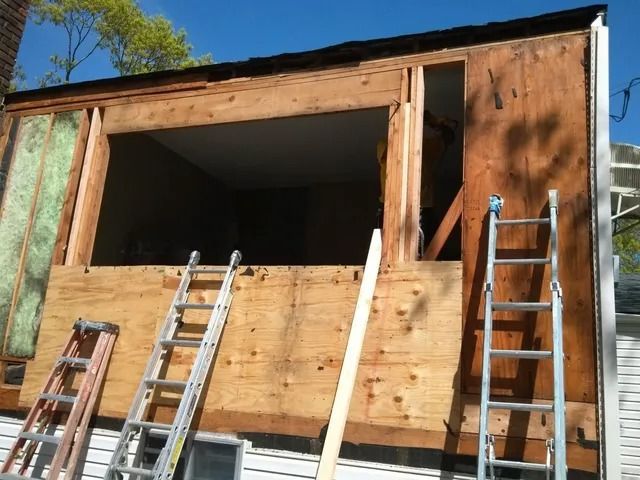 Partially built wooden structure with several ladders leaning against it under a blue sky