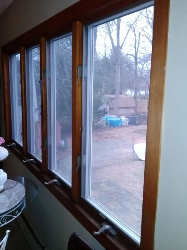 Sunroom windows overlooking a backyard and leafless trees on a cloudy day
