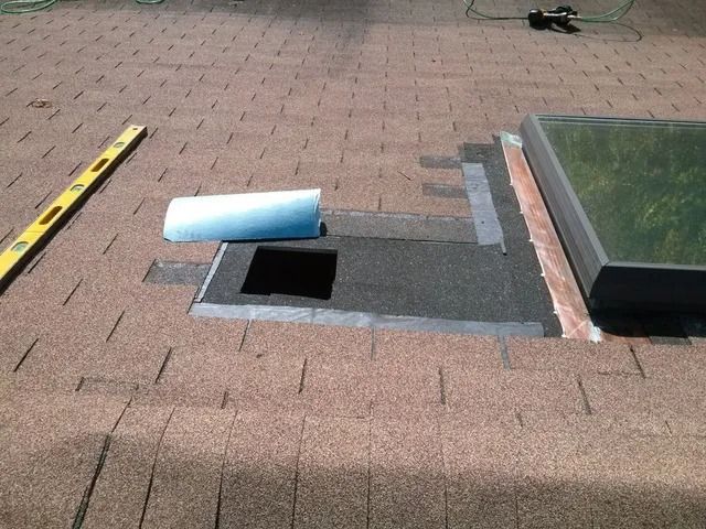 Roof with open vent opening, blue pipe segment, and measuring tape on shingles