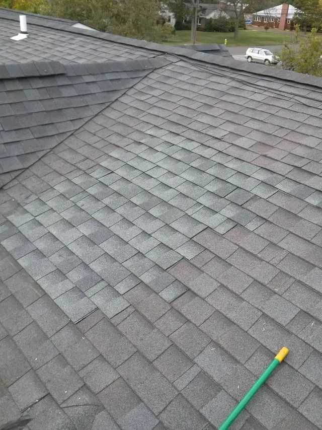 Rooftop with gray shingles and a green-handled tool resting on the roof.