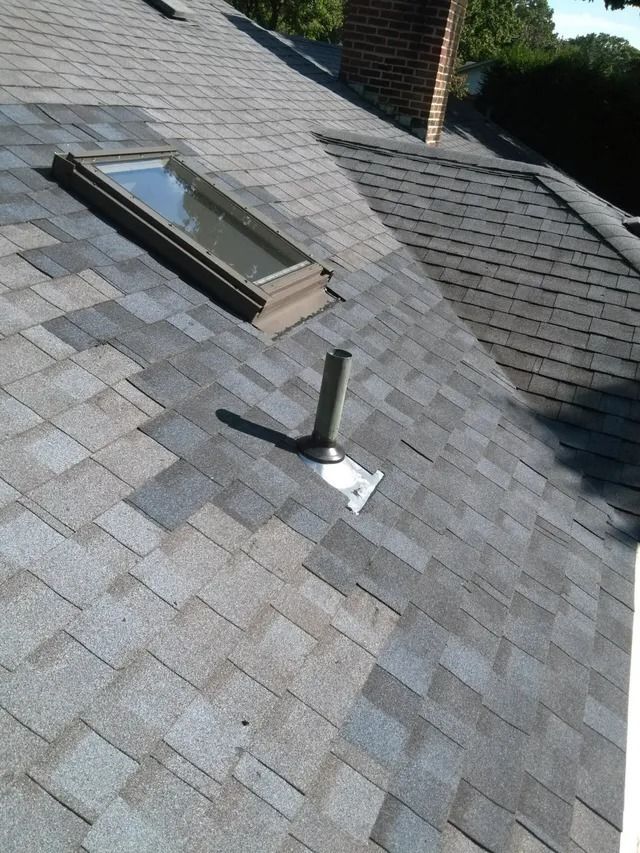 Gray shingle roof with a skylight and a vent pipe near the ridge