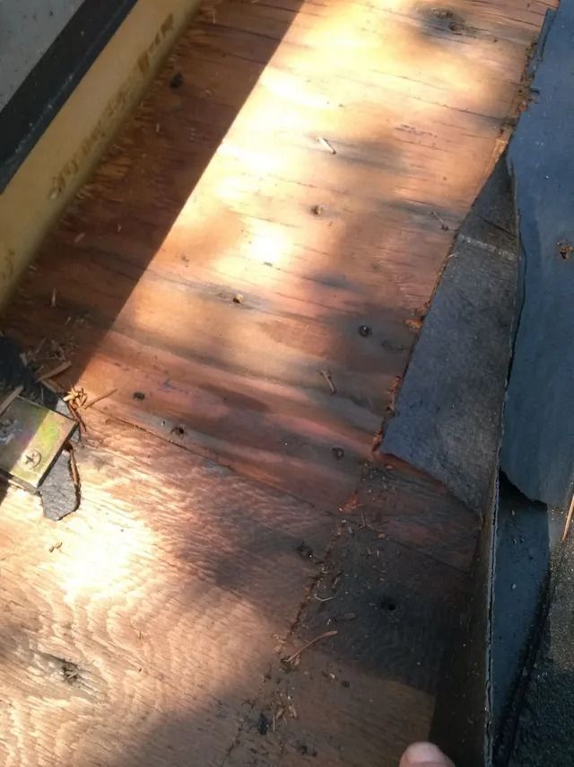 Sunlit wooden floorboards with visible water stains and shadows