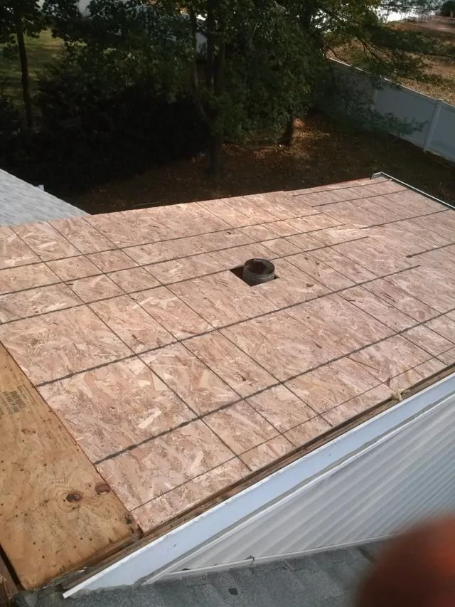 Roof under construction with plywood sheathing and a small vent opening near the center