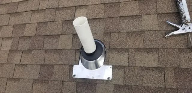 Roof vent pipe with white cap on brown shingle roof