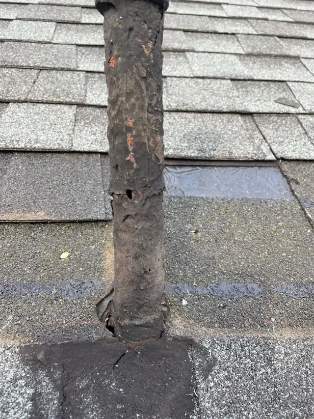 Damaged roof shingles around a weathered vent pipe with flashing at the roof base