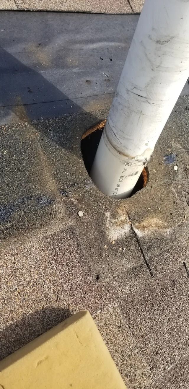 Close-up of a white pole set in cracked asphalt beside a yellow curb edge