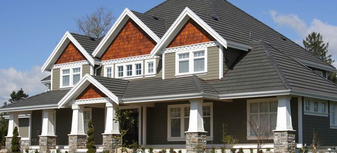 Large gray-and-white house with red brick accents and a covered front porch under a clear sky