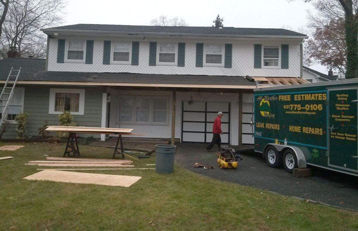 Two-story white house with a front porch and a green sign trailer in the driveway
