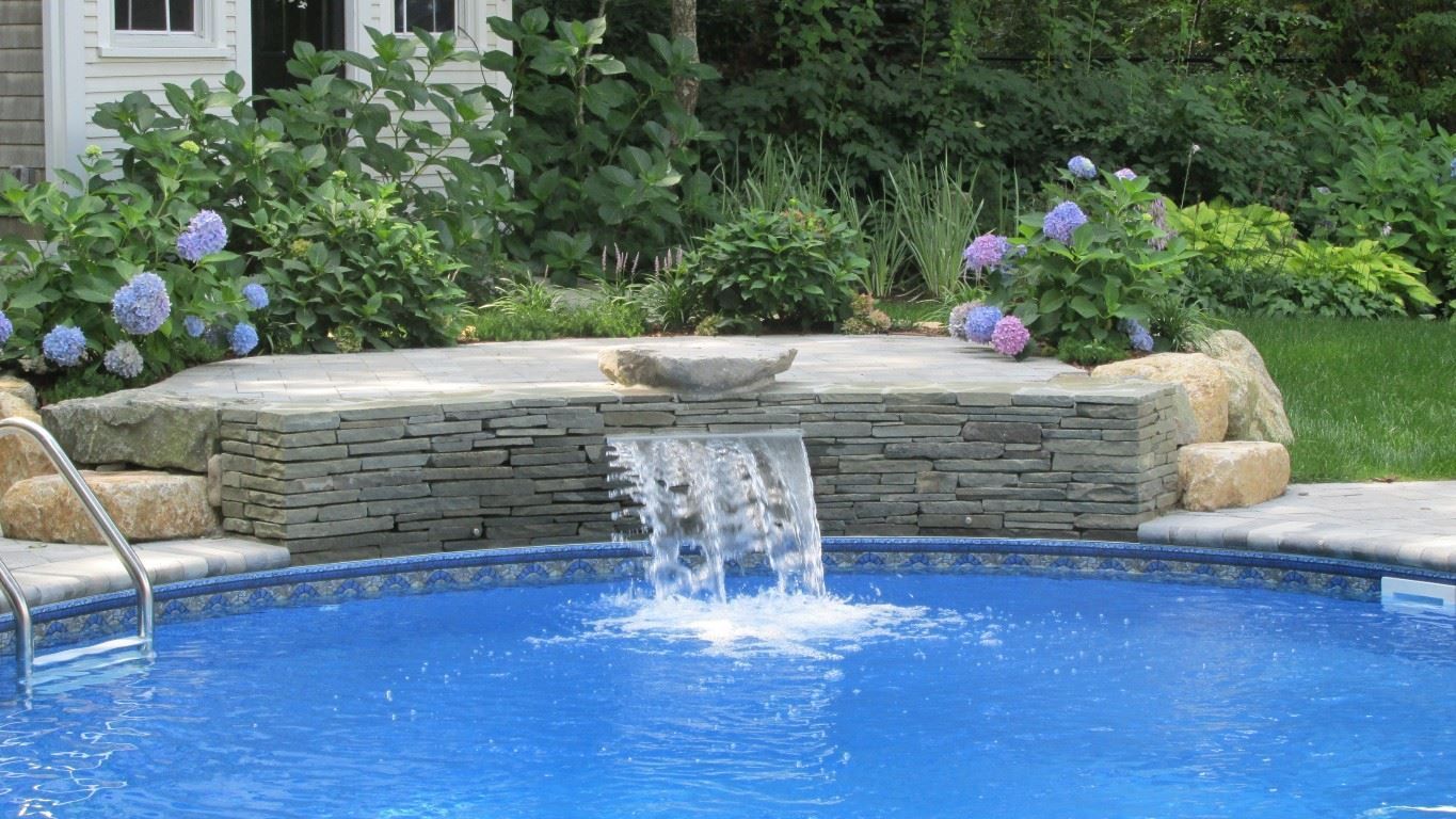 Pool with waterfall feature and surrounding greenery.