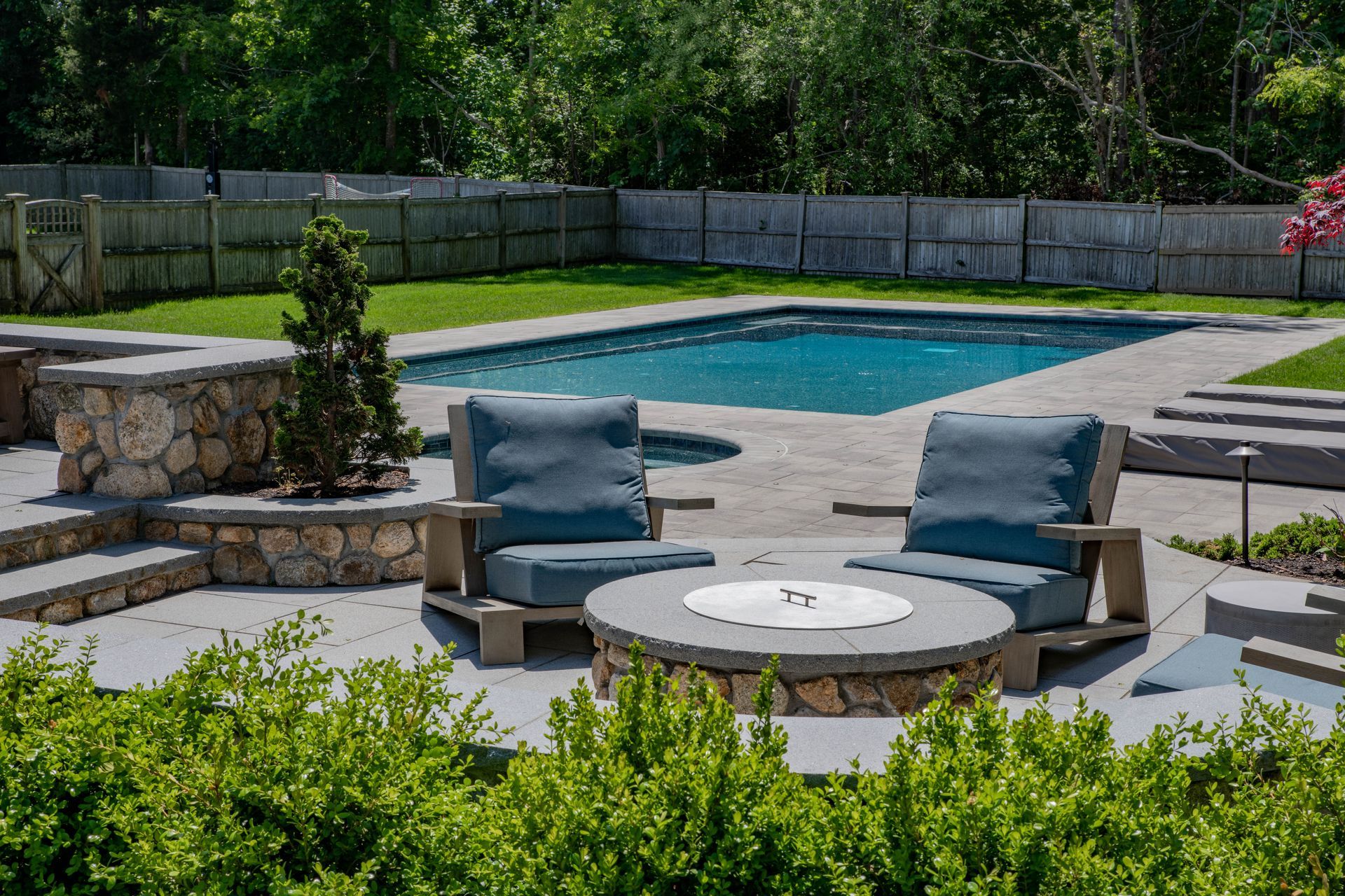 Outdoor seating area with a fire pit, overlooking a pool and grassy backyard.