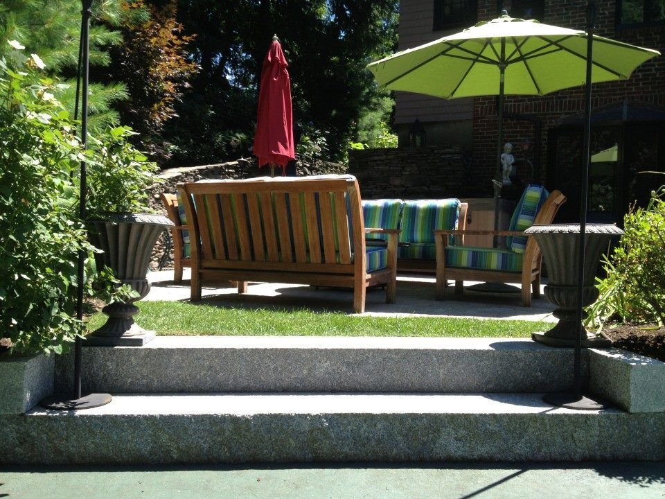 Patio with wood furniture, umbrellas, and potted plants.